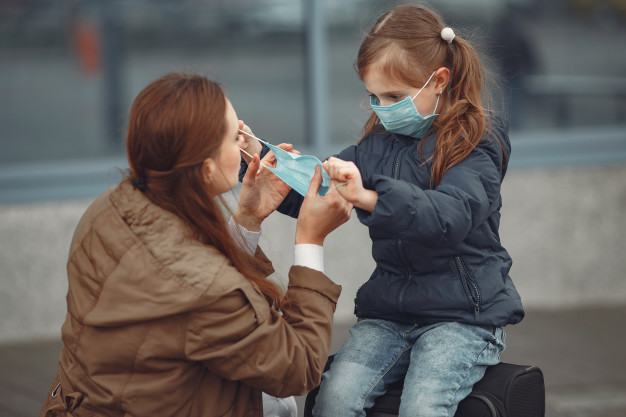 A mother and child wearing surgical face masks in public during COVID-19